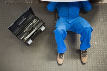 Mechanic lying and working under car at the repair garage